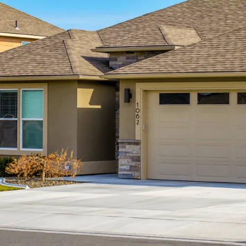 Freshly re-stuccoed single-story home in tan with stone accents and a clean driveway