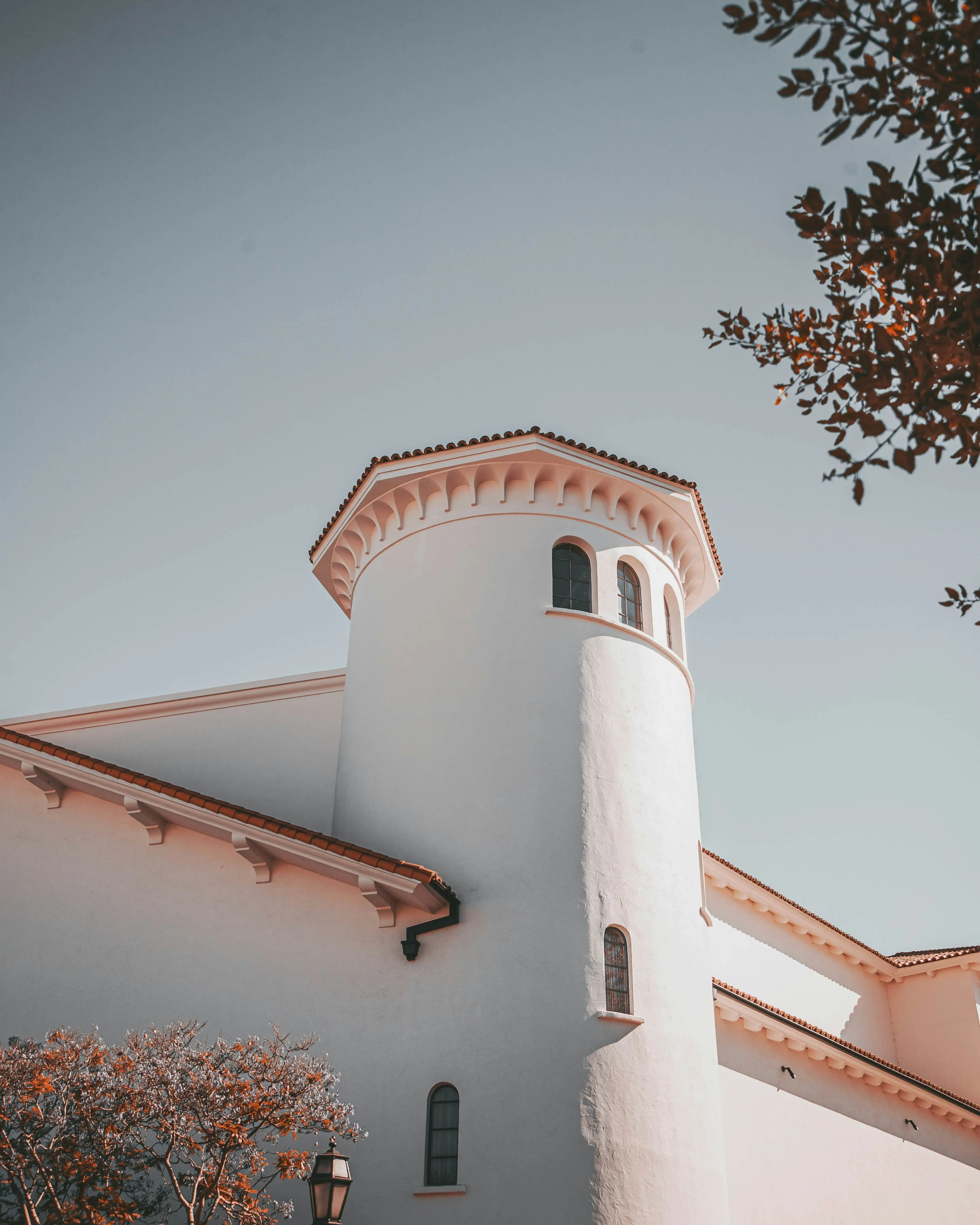 Sunlit Spanish-revival tower with smooth white stucco walls and a clay-tile roof