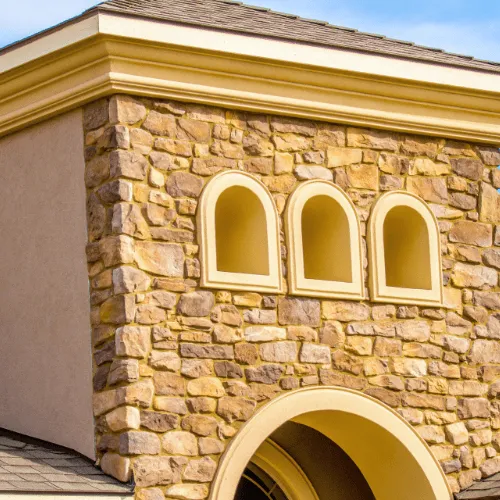 Stone-veneer parapet wall with arched alcoves trimmed in crisp gold plaster