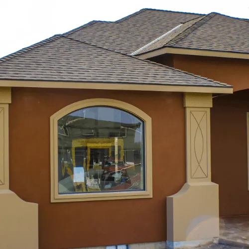 Terracotta stucco facade with an arched picture window and decorative plaster columns